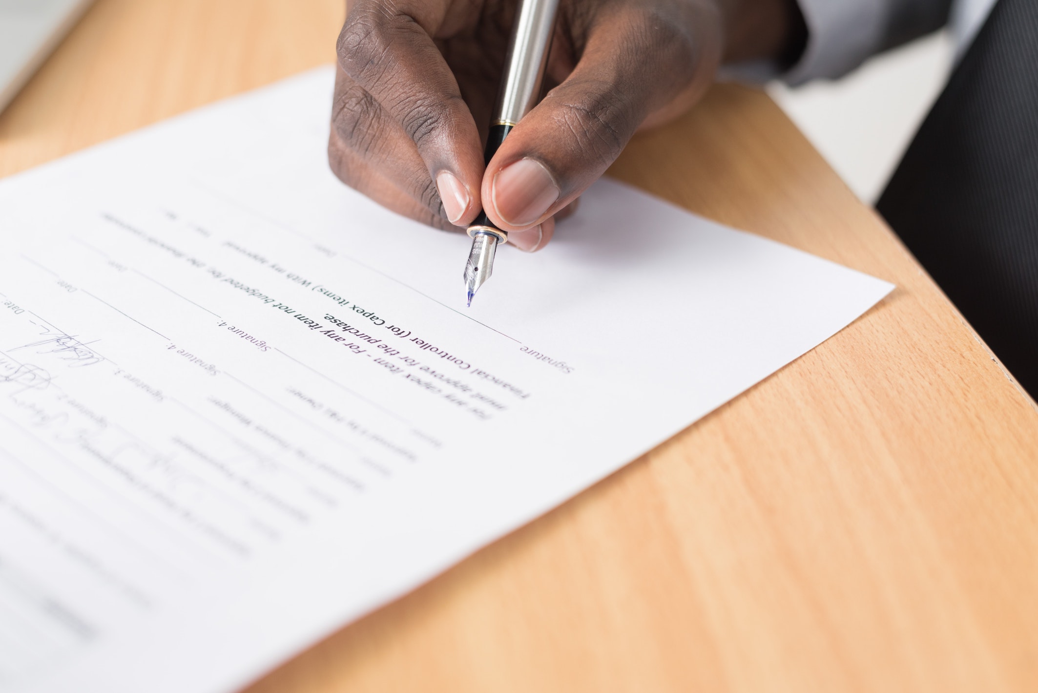 An image of a hand holding a pen signing a contract