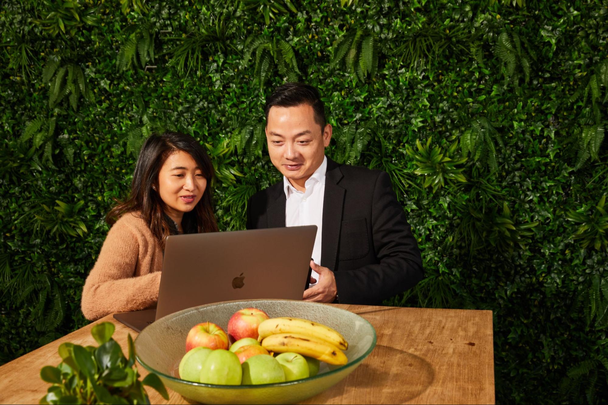 two employees having a discussion in front of a laptop