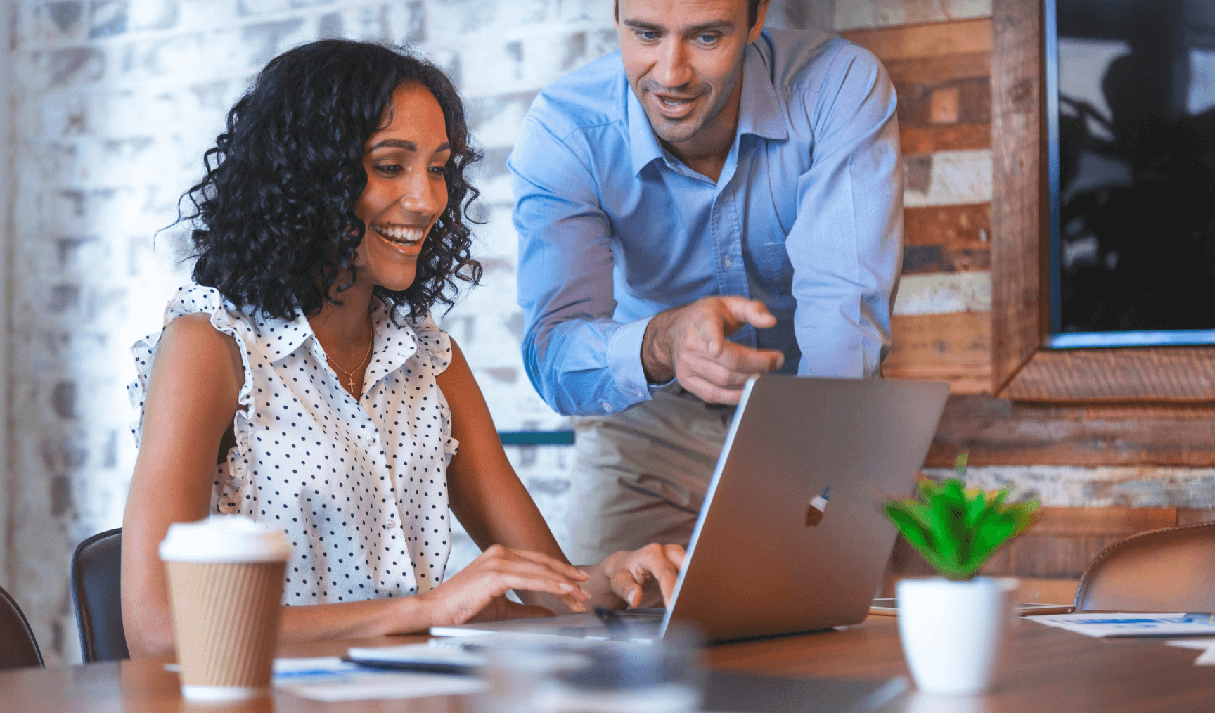 two employees pointing at the laptop and discussing