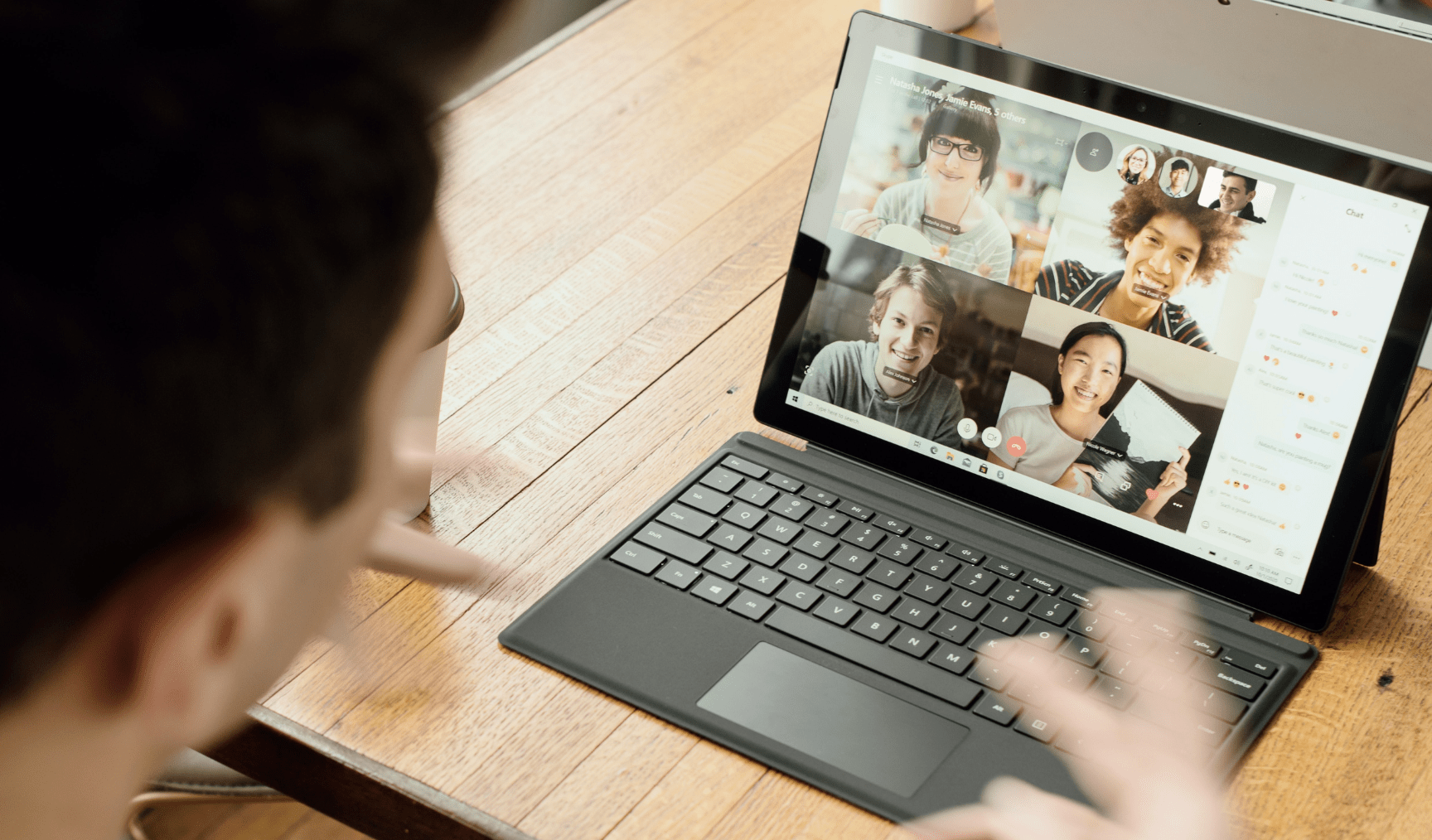 Man sits on a conference call, with his colleagues visible on his laptop screen