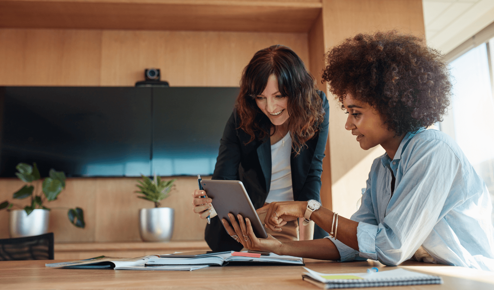 a woman discussing something on a tablet with another woman