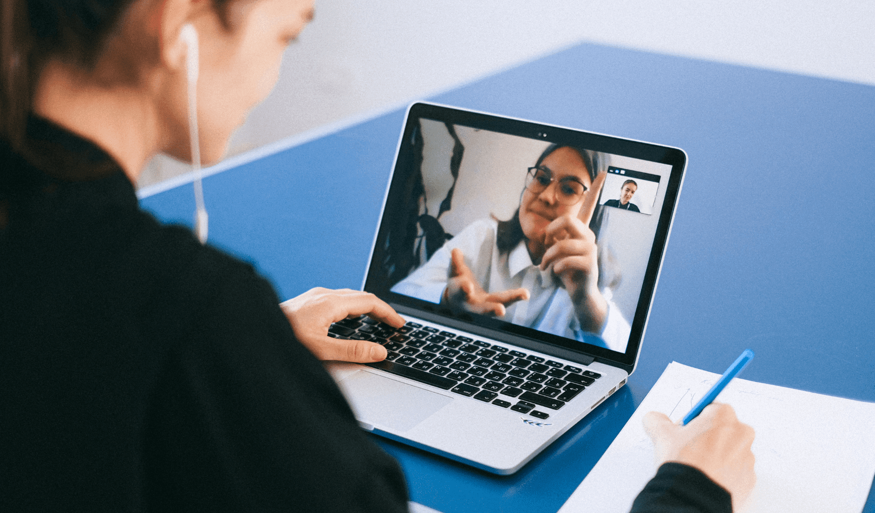 Woman sits at laptop, on a conference call with a colleague