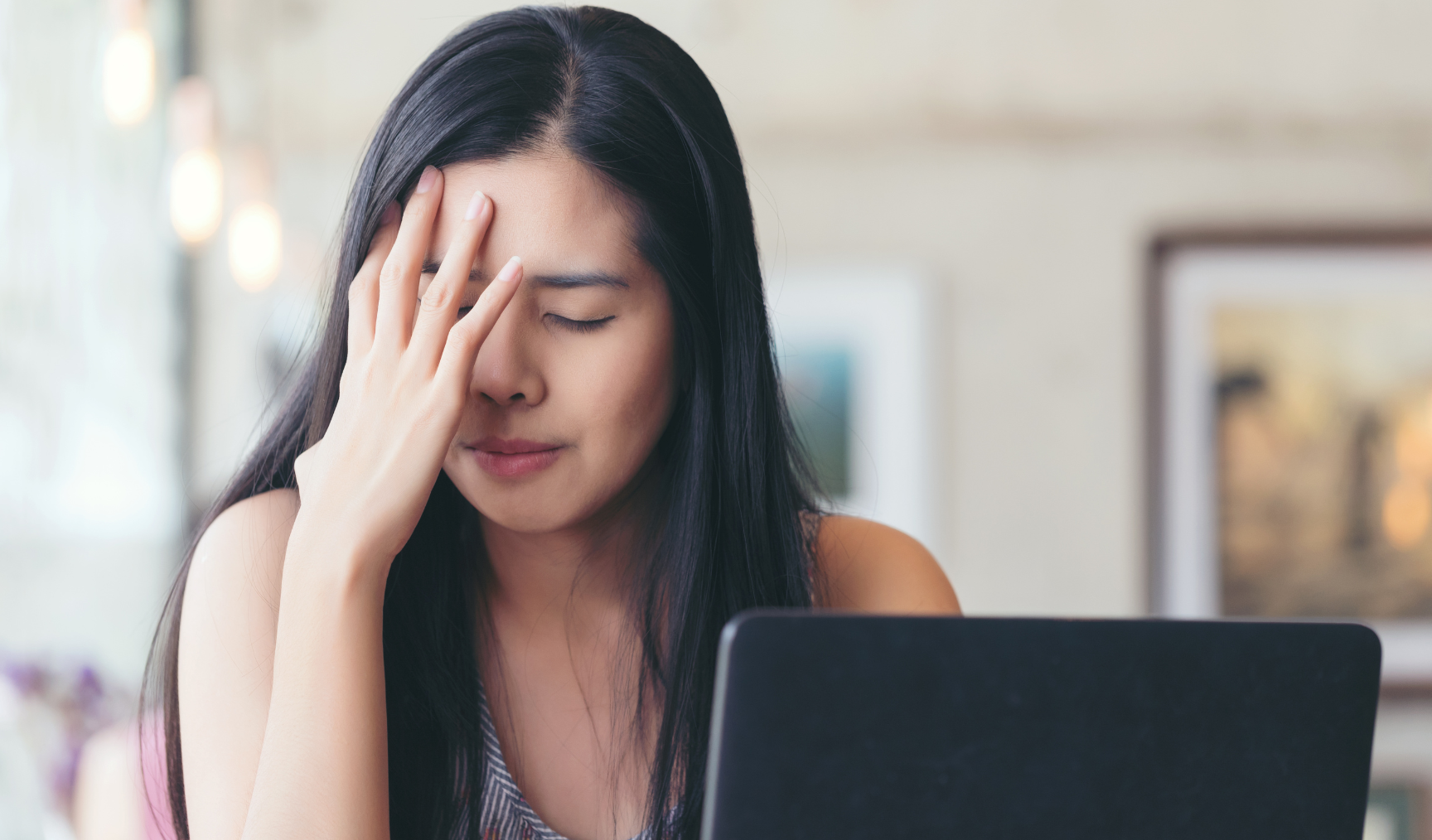 woman with her hand on her head in front of her laptop