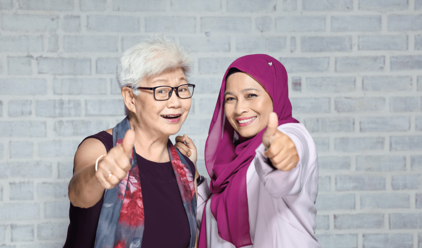 two women smiling at the camera and giving thumbs up