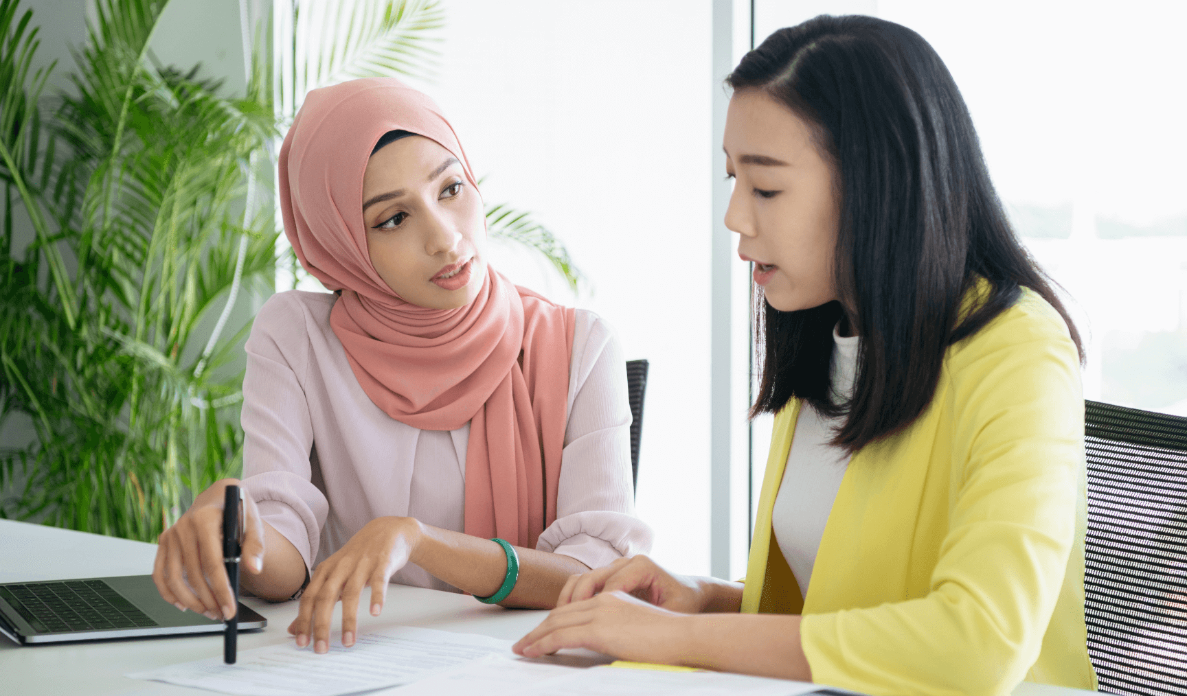two female colleagues having a discussion and looking at a laptop
