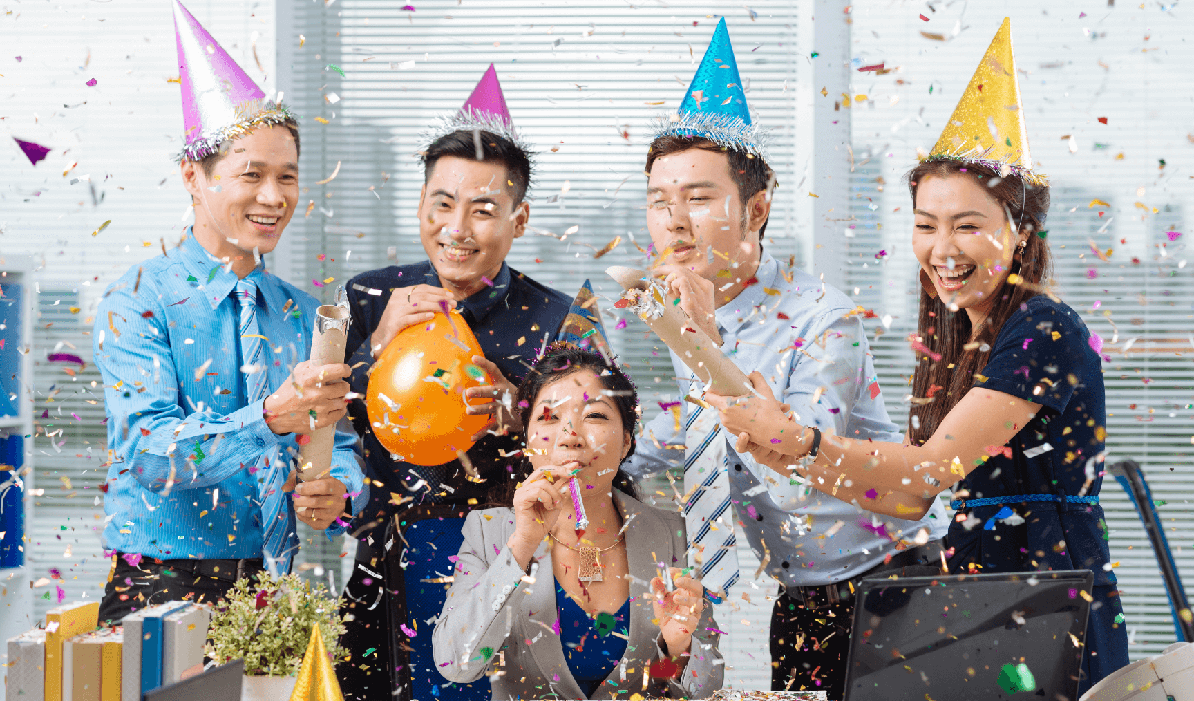 a group of colleagues wearing party hats and celebrating