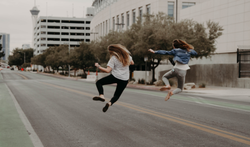Two women jumping for joy on a city street