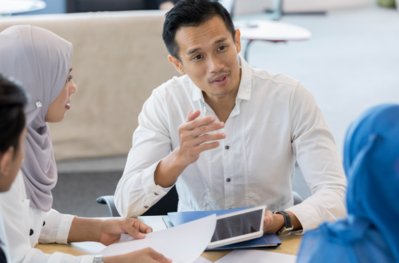 guy holding a tablet while chatting with colleagues