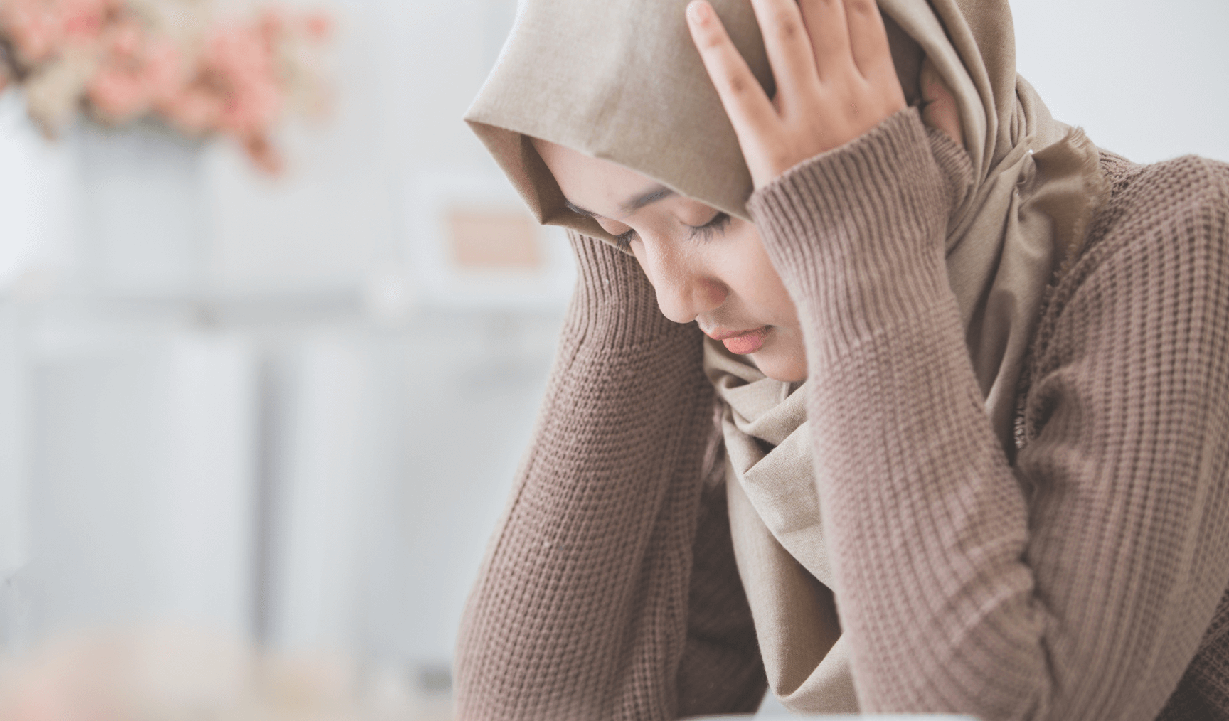 woman holding her head while looking down 