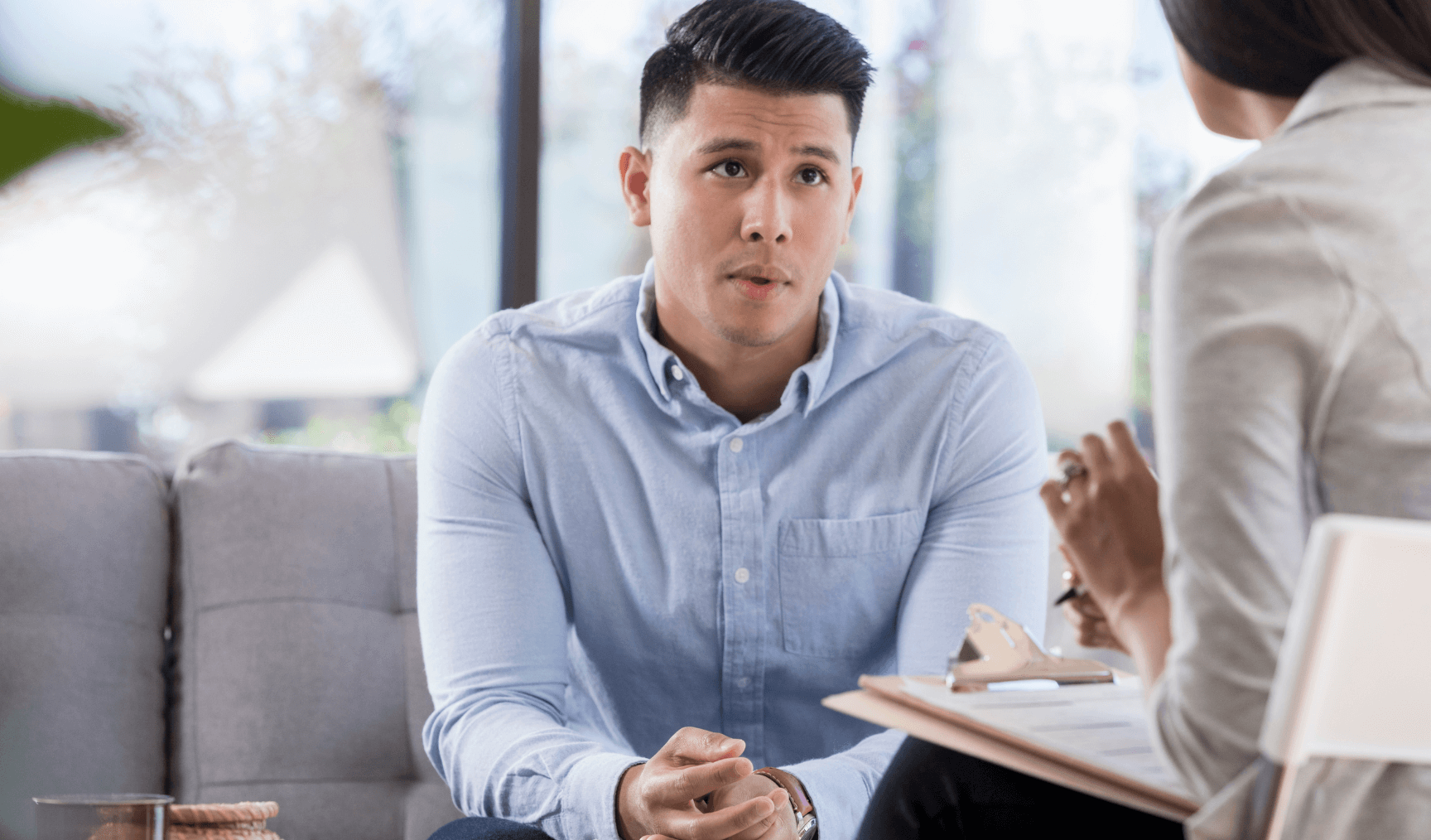 man talking to his colleague in the office with his hands clasped together