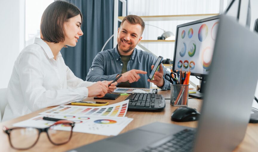 People looking at computer screen at a desk.