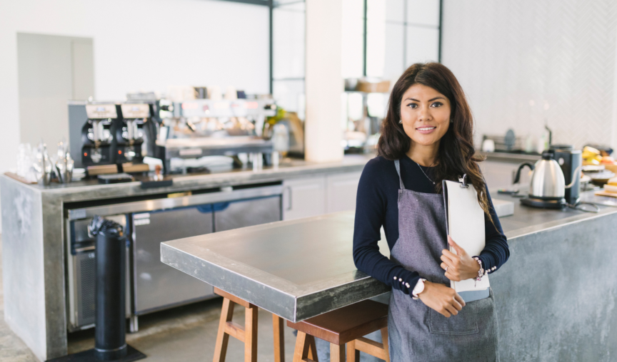 woman working at a cafe holding a clipboard