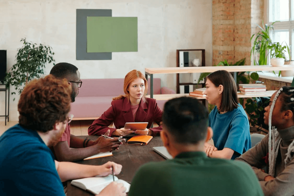 group of diverse colleagues seated around a table discussing 