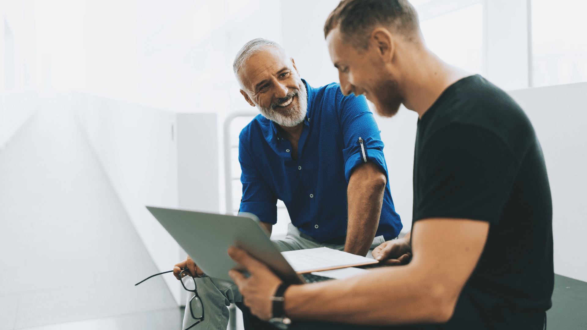 Two men discussing something over a laptoip