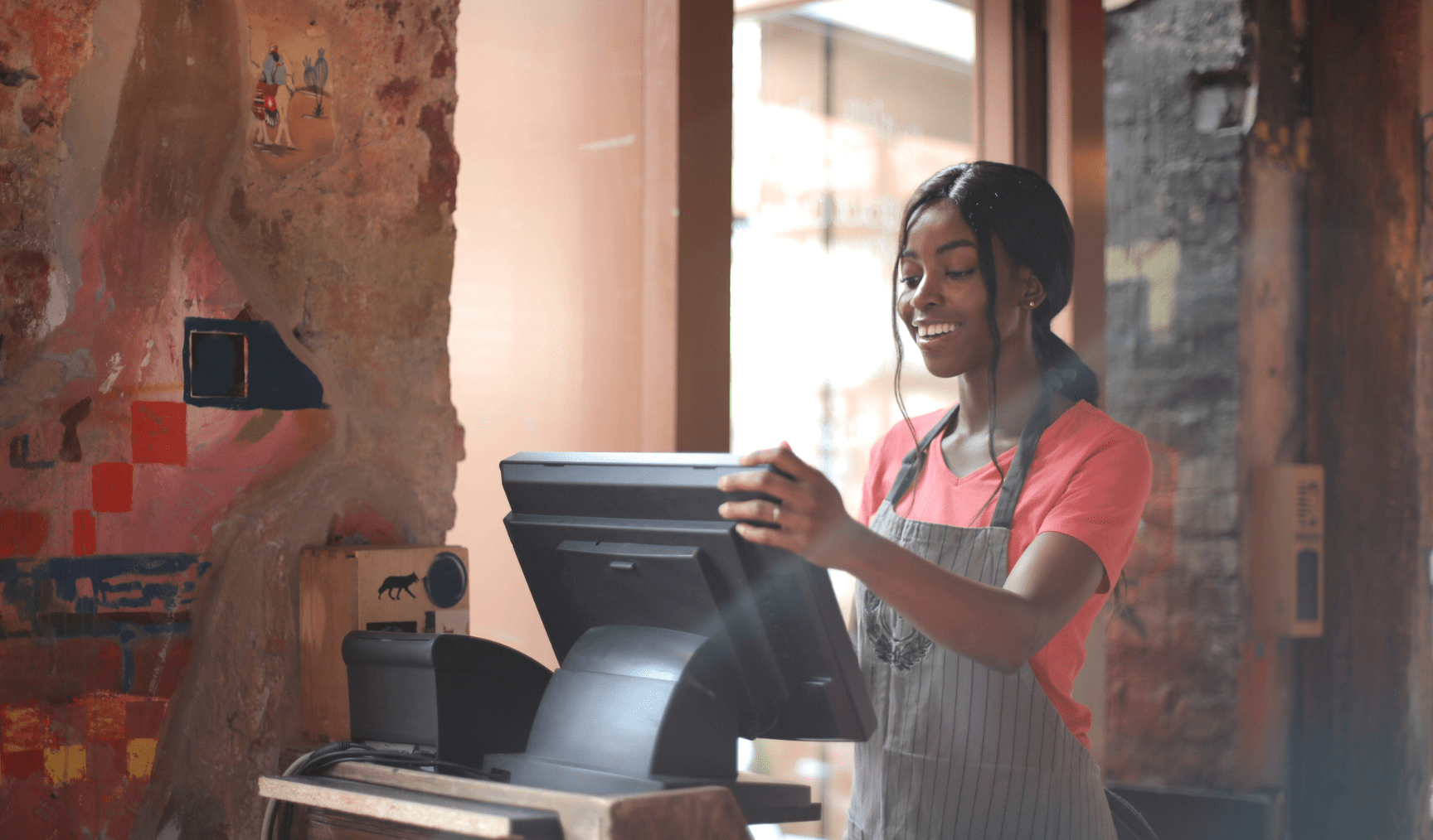 Woman stands working at a till in a cafe