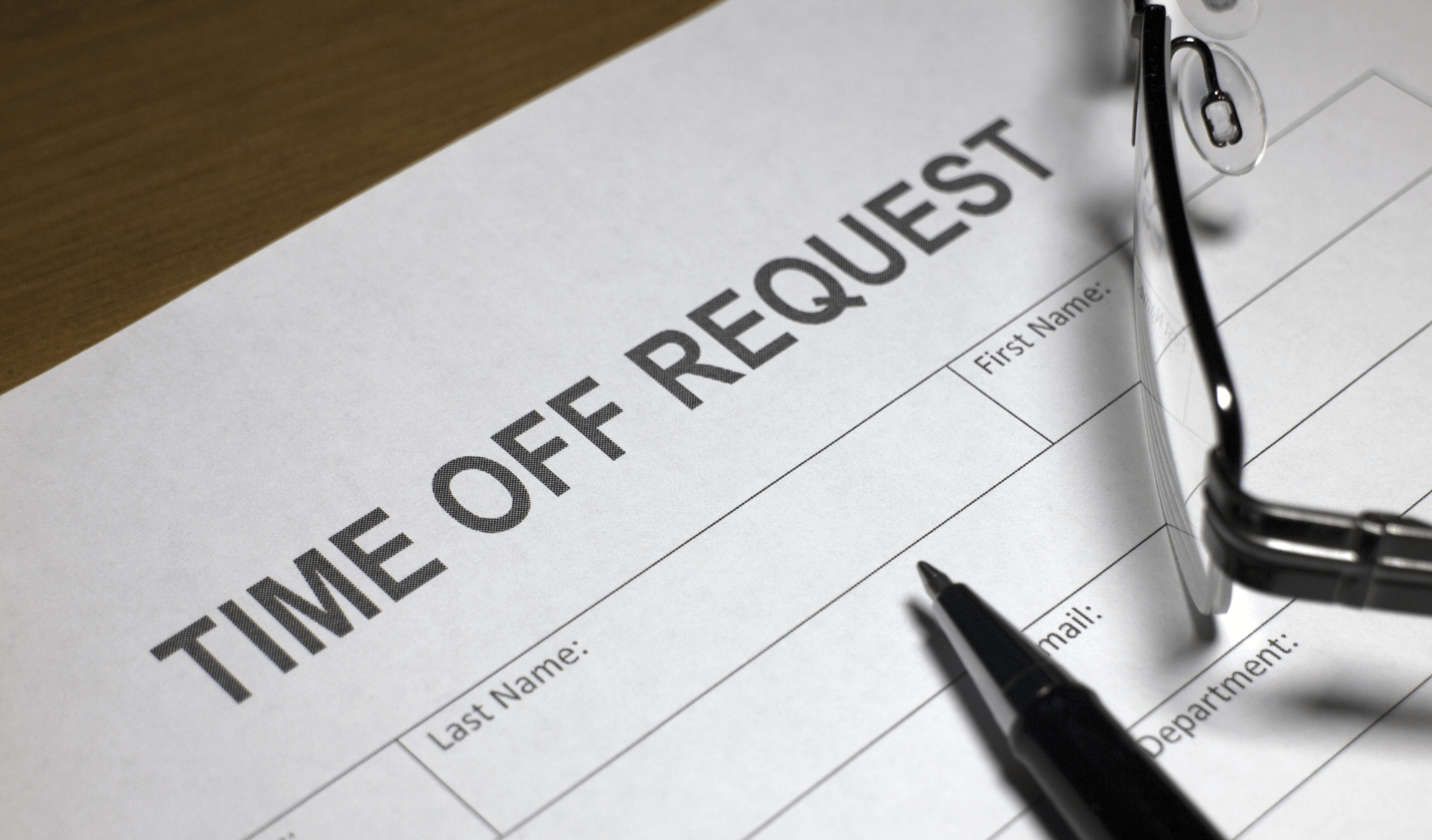 a time off request form with a pen and glasses on top of it