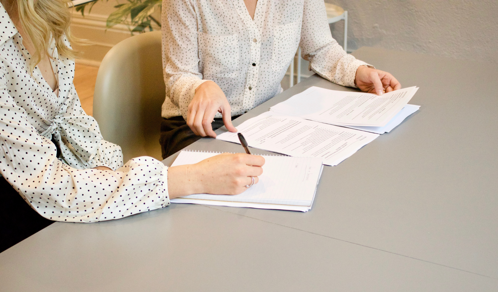 Two people sit at a table reading through documents