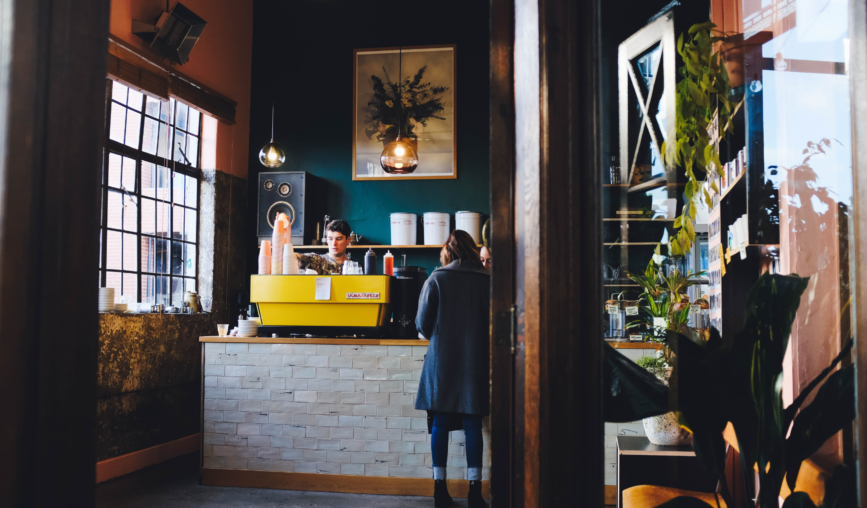 A cafe in Auckland, one barista working behind the coffee machine and a customer at the counter
