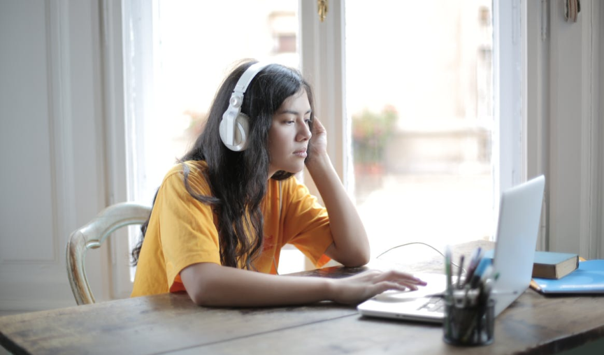 woman listening to music with her headphones while doing work on her laptop