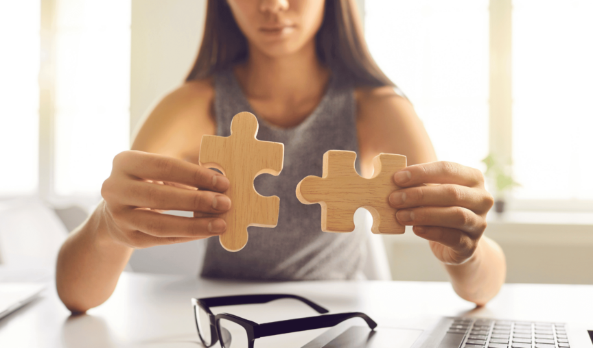 This is an image of a woman fitting 2 puzzle pieces together.