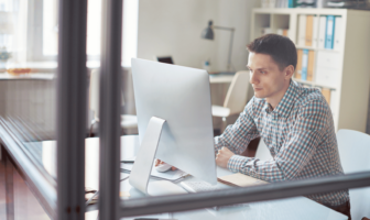 Man working at his computer in a closed office.