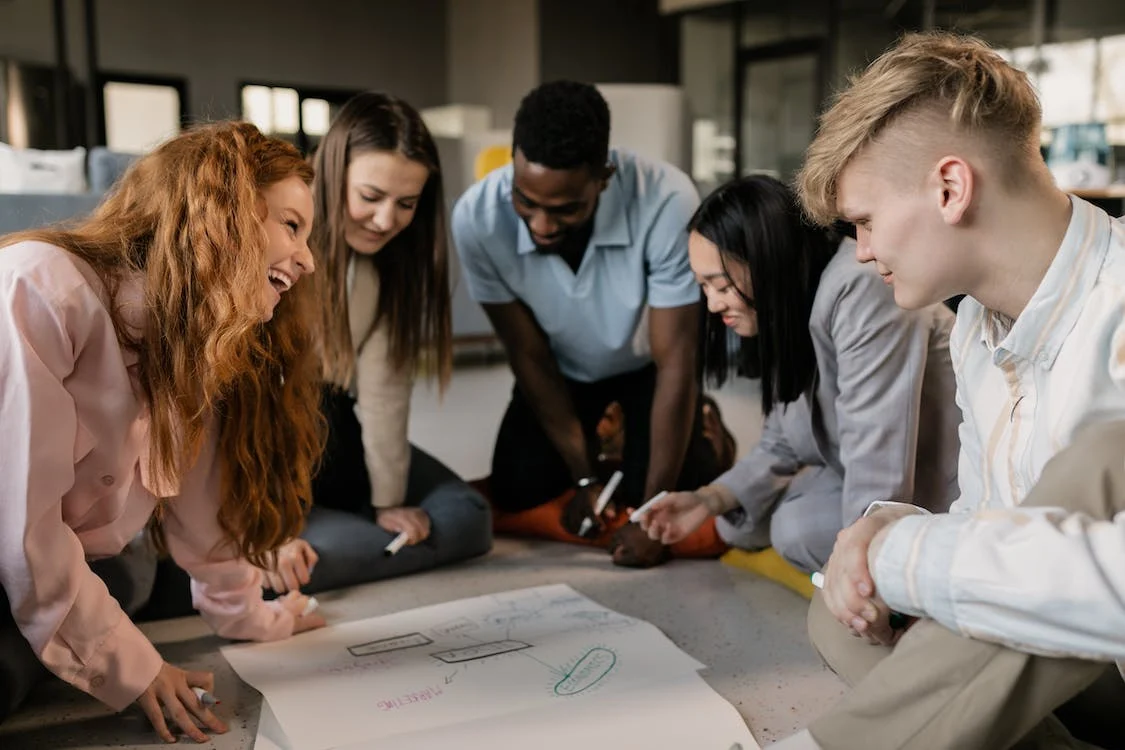 group of diverse employees huddle around a table brainstorming