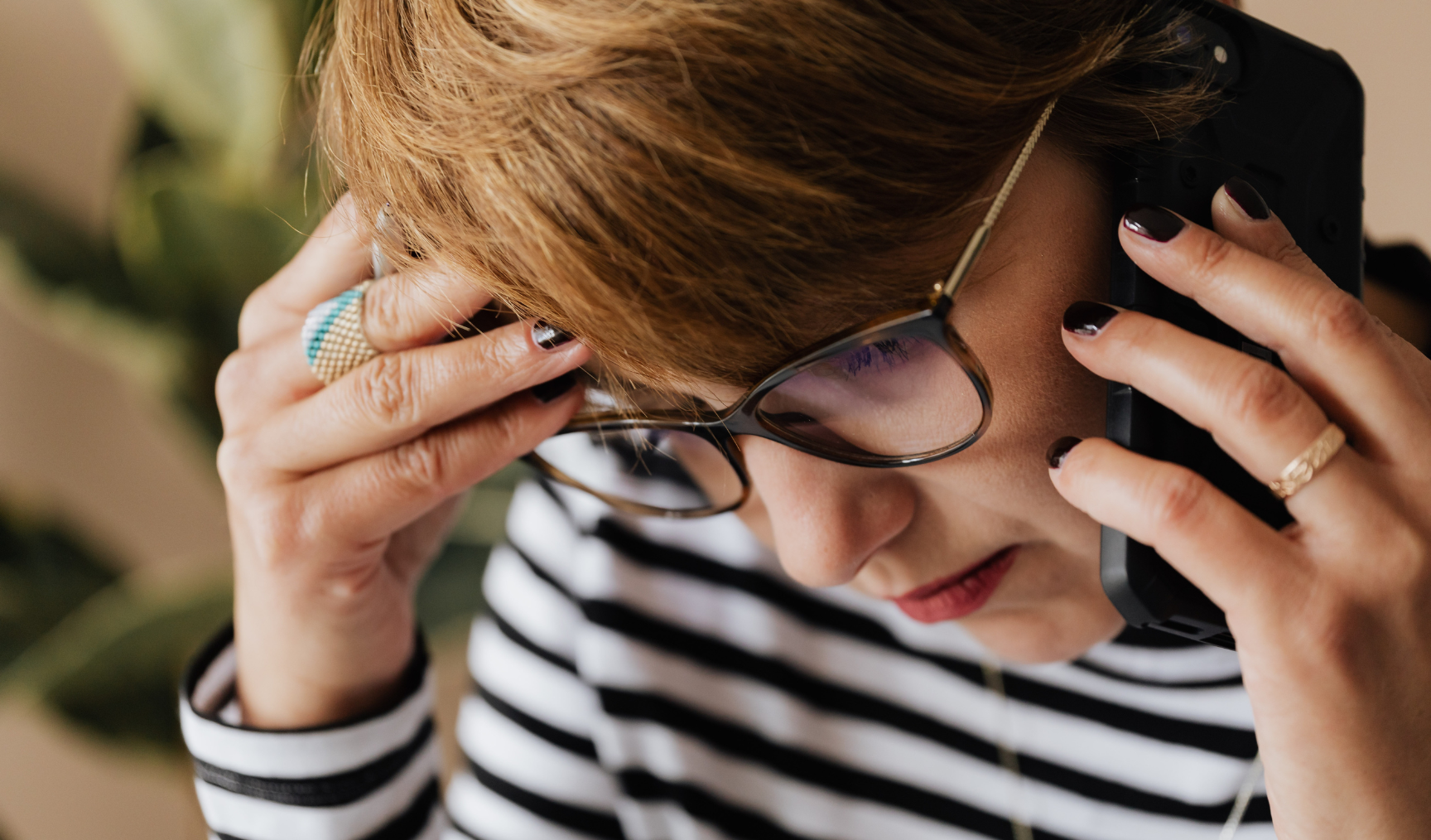 Woman is on the phone, hand to her temple, looking concerned