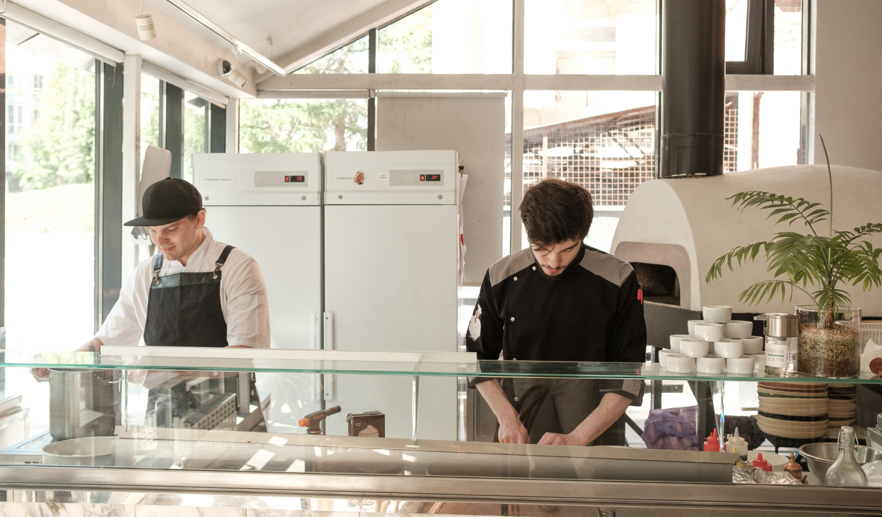 Two people work behind a commercial kitchen counter
