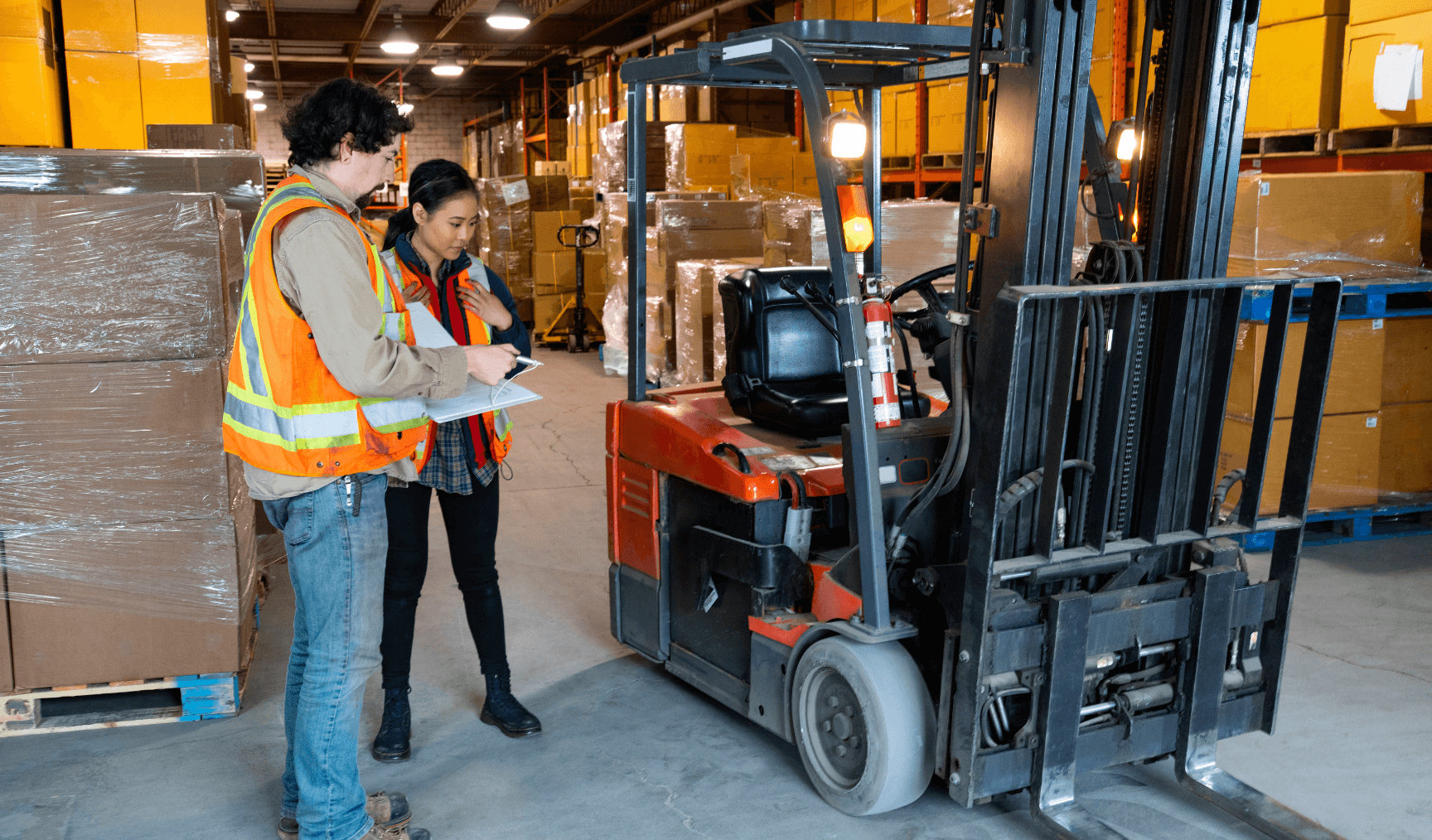 two employees in the warehouse looking at a forklift machine