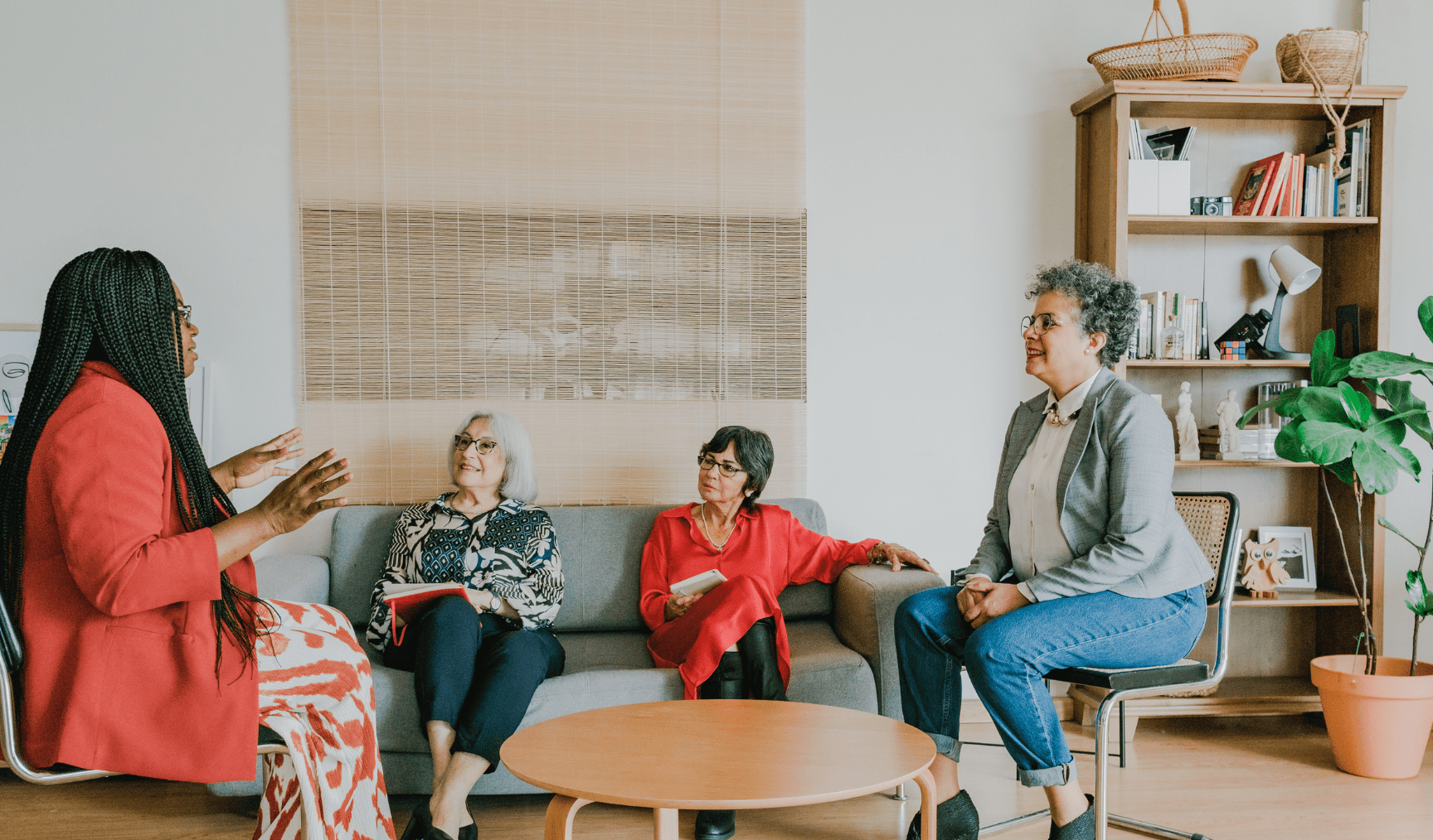 A group of people sit around a coffee table in a casually decorated office room
