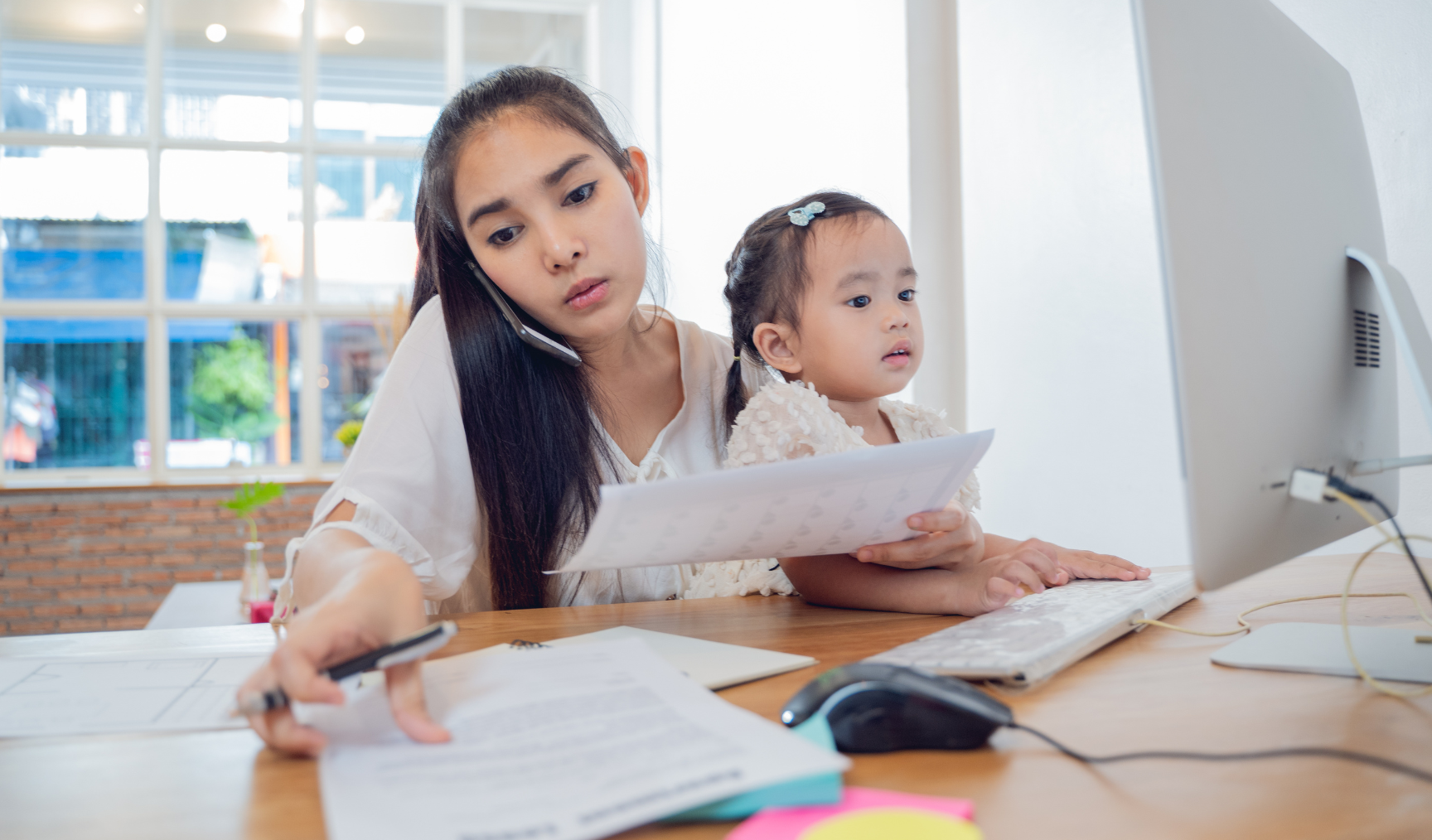 mom holding her baby while trying to work from home