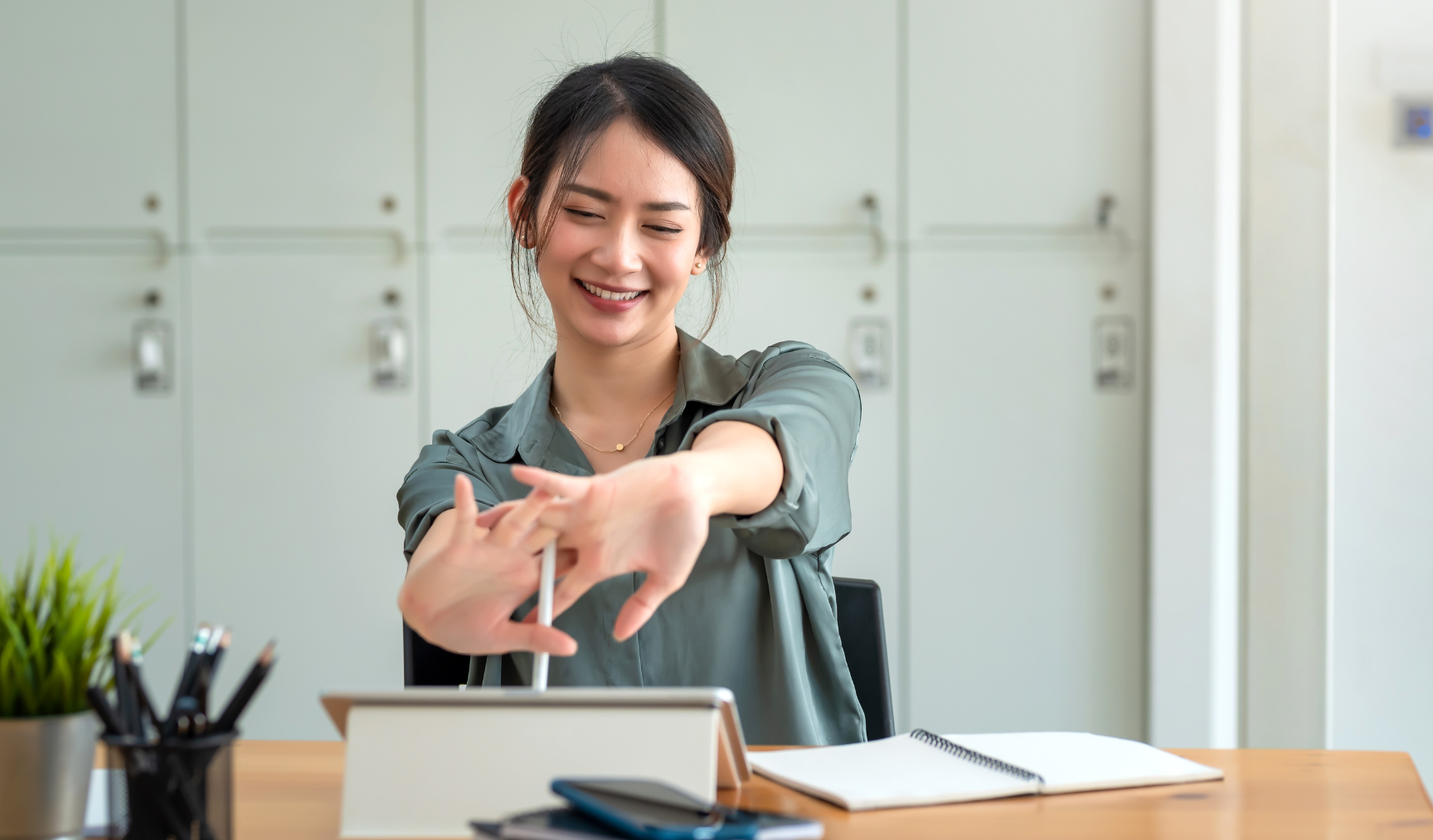 woman smiling and stretching at her desk