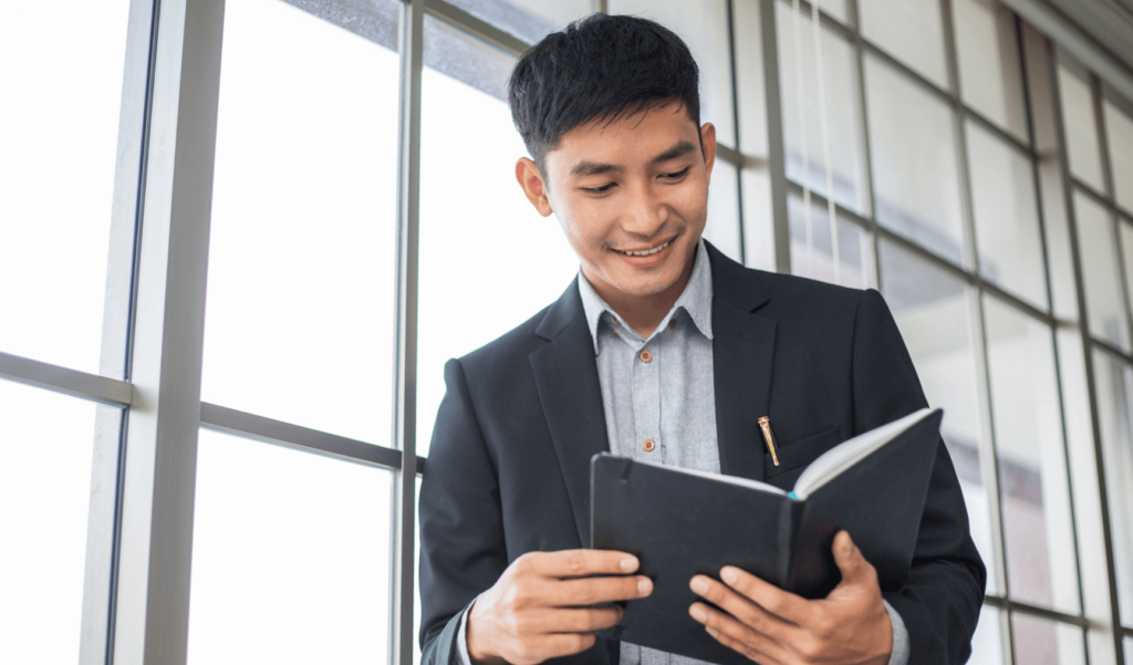 man smiling and looking at a notebook