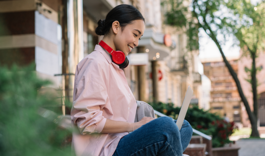 woman typing on her laptop while seated outdoors