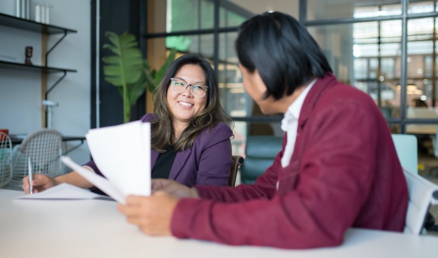 two employees laughing adn having a discussion in the meeting room