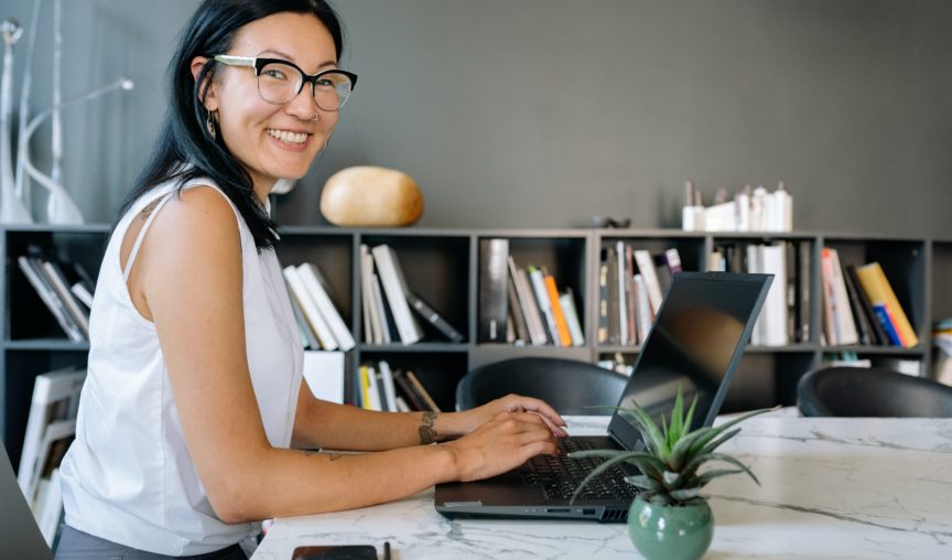 woman sitting at her desk typing while smiling