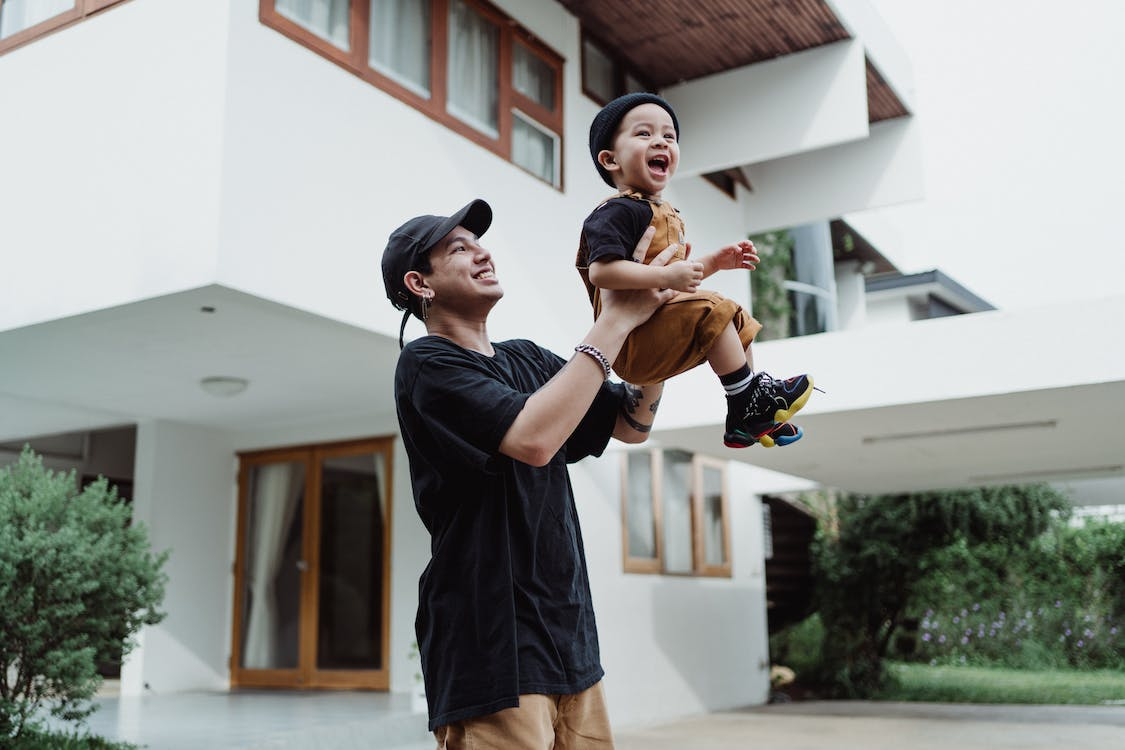 dad playing with his kid in front of the house