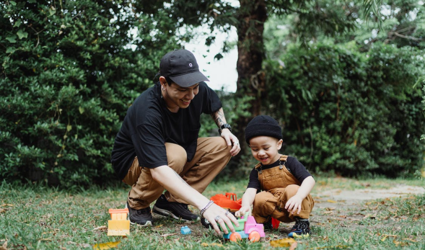 dad playing with his kid and some toys in the garden