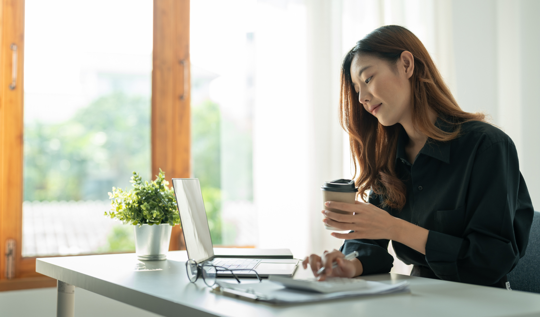 woman at her work desk while holding a cup of coffee