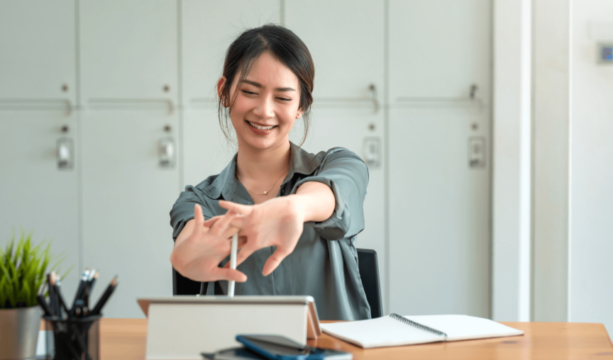 woman smiling while stretching her arms at her desk