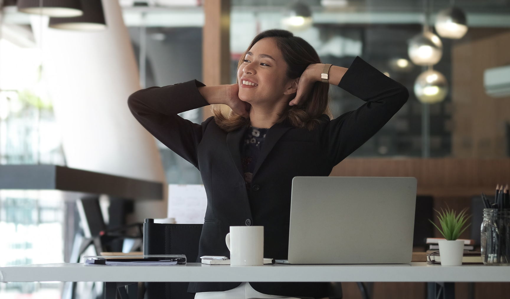 Woman stretching and smiling at her desk