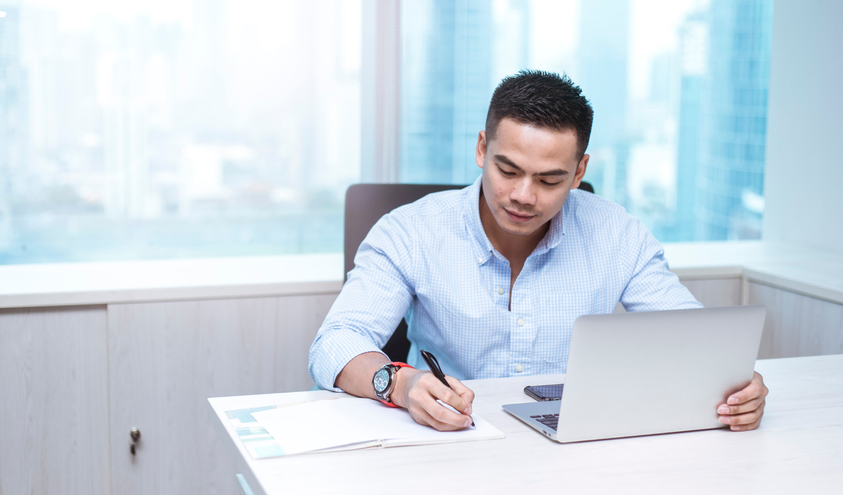 Man writing something on a piece of paper at this work desk