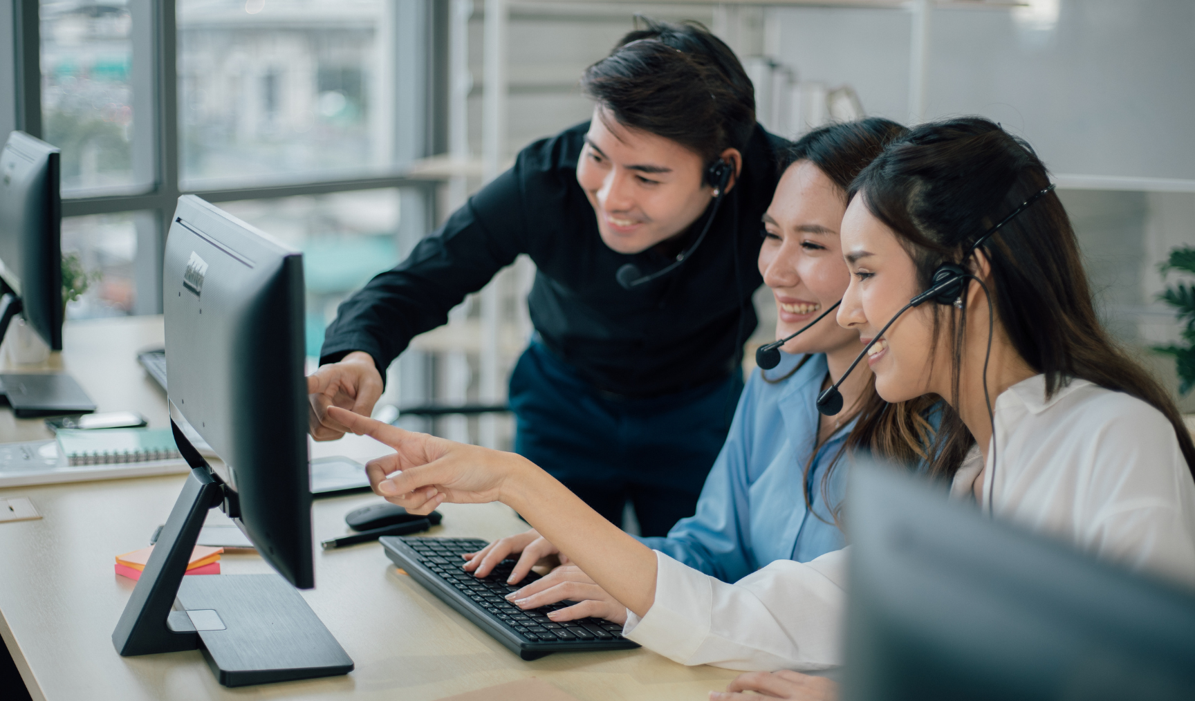 bunch of colleagues chatting and pointing to something on the computer screen