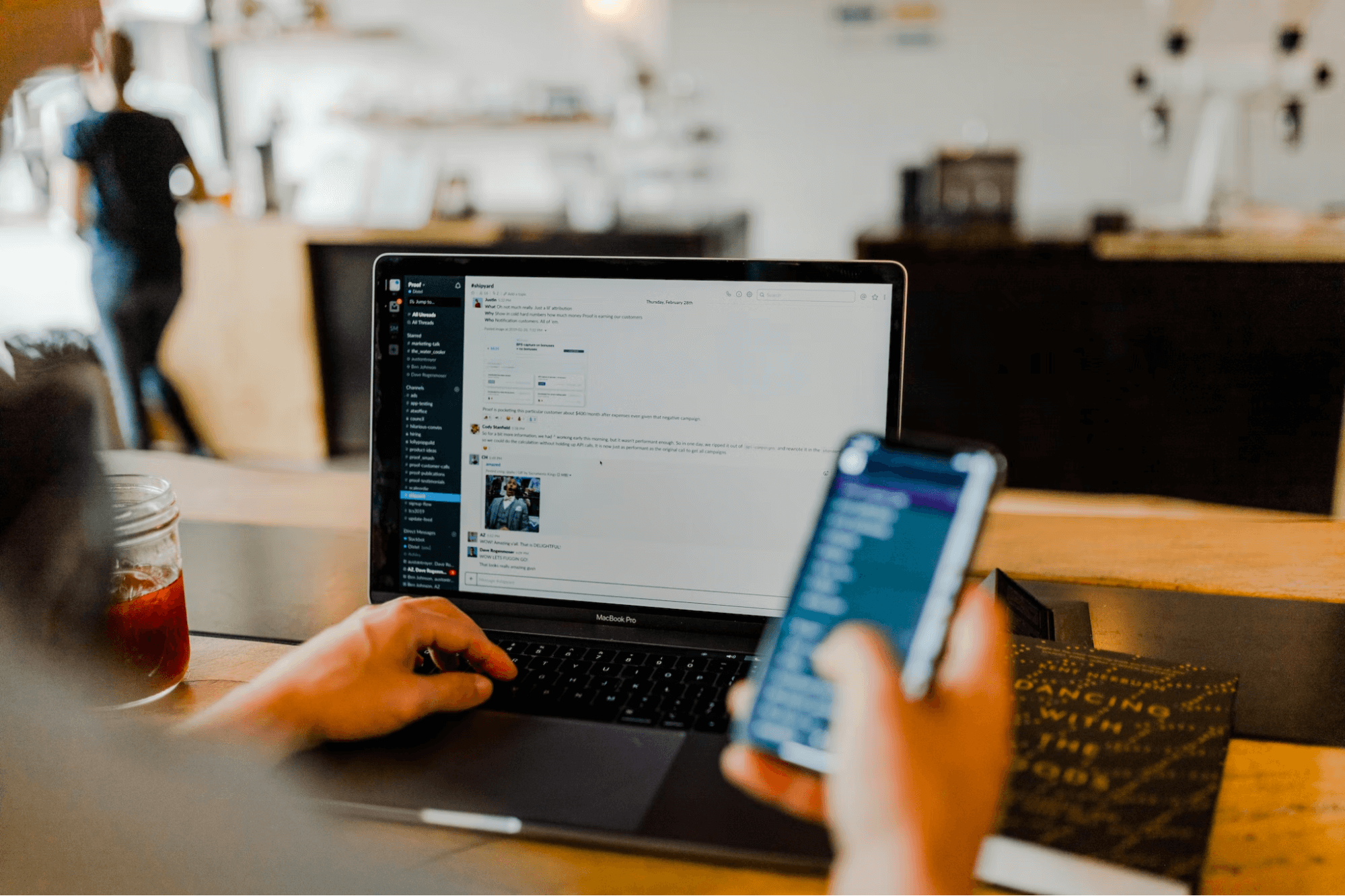 guy using his laptop for Slack and his mobile phone in his right hand