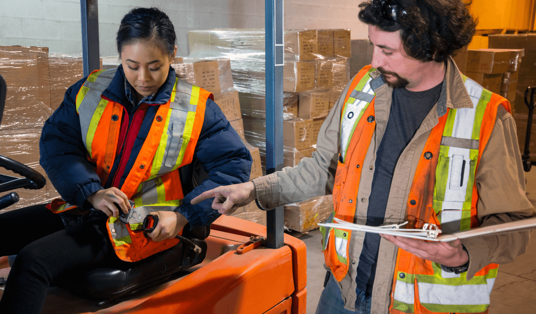 two colleagues in the warehouse learning how to use machinery properly