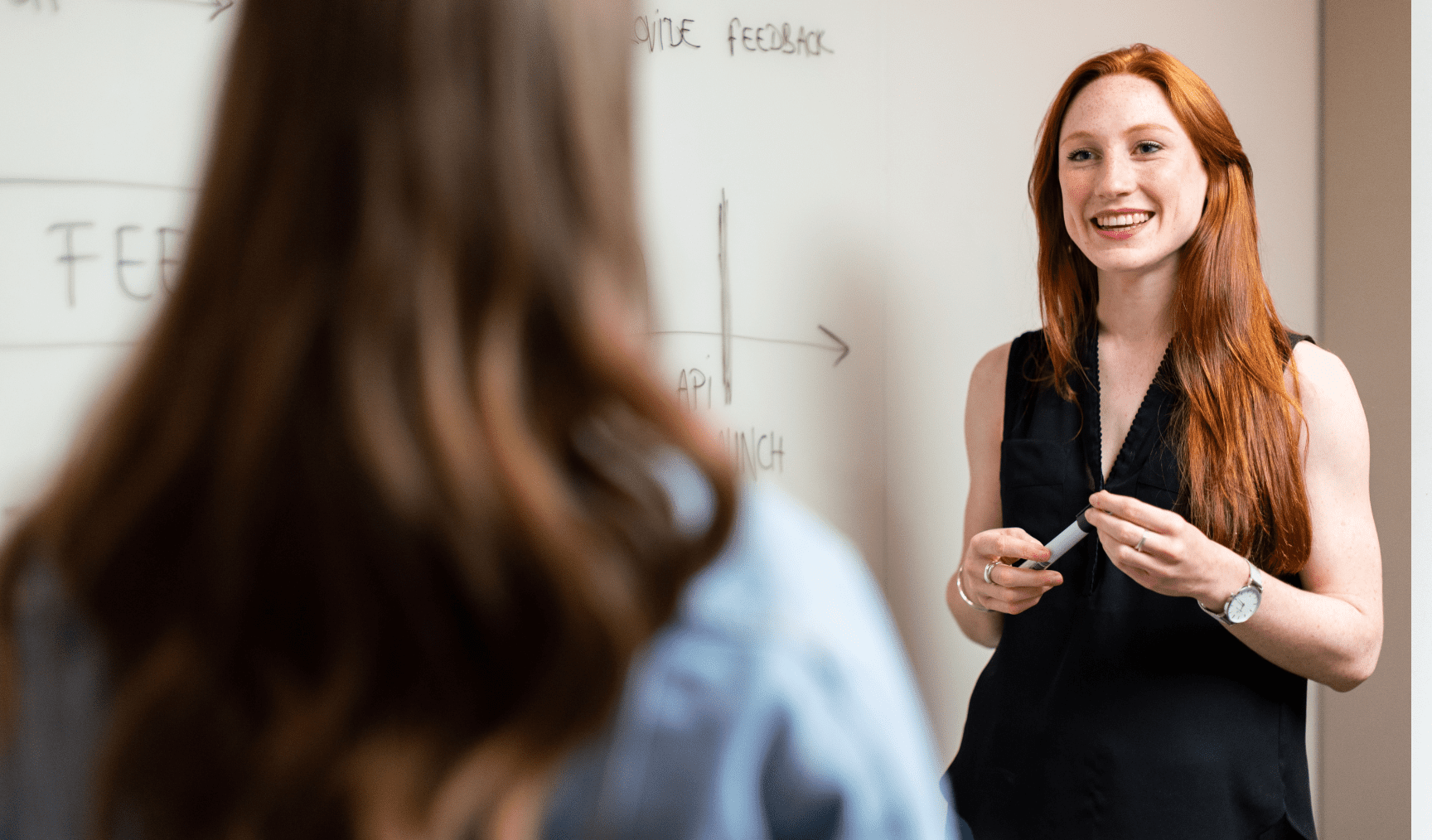 Woman stands at a whiteboard, discussing ideas