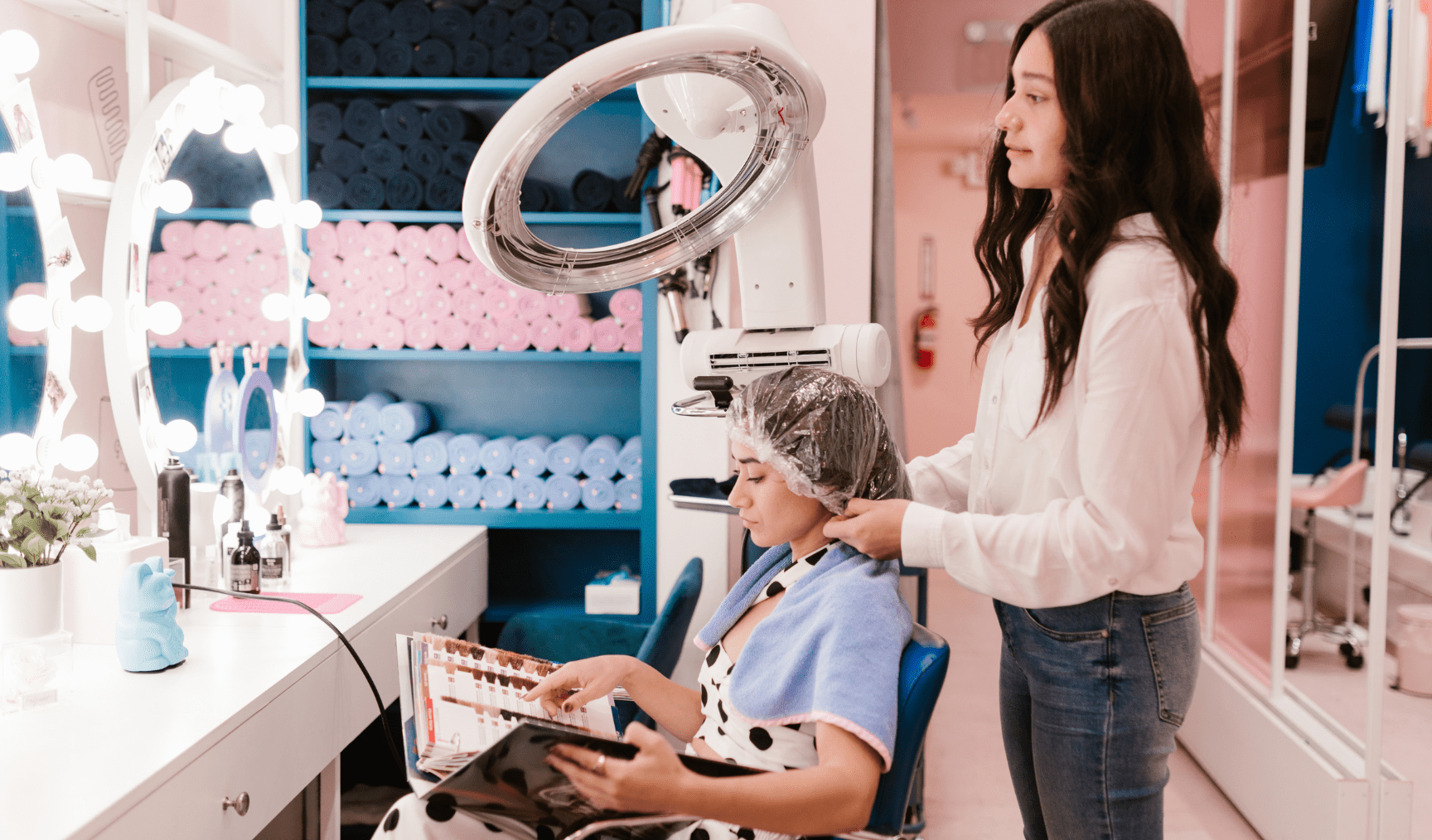 A woman sits in a chair while a hairdresser fixes her hair